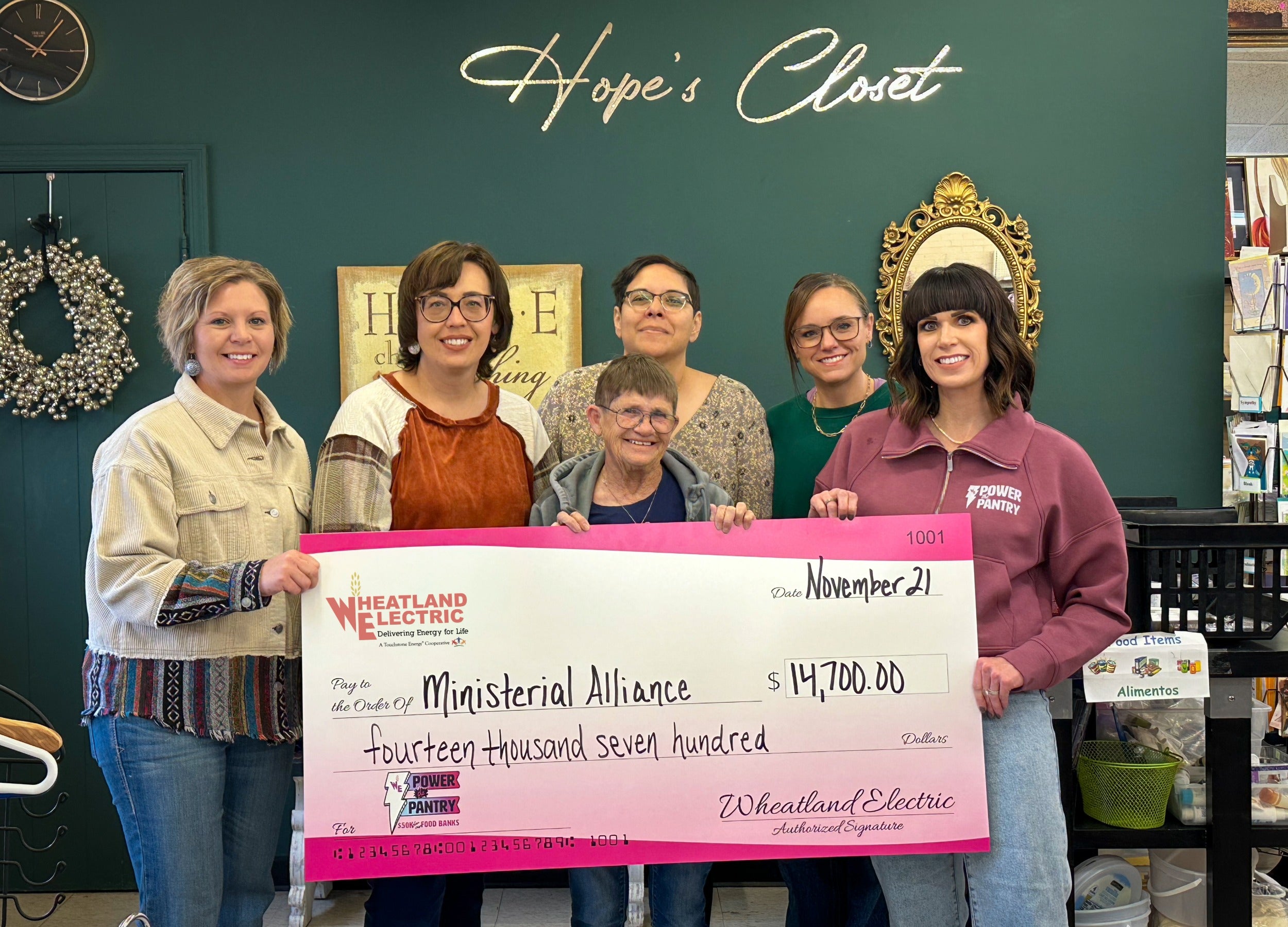 Alli Conine (right), director of member services and corporate communications at Wheatland Electric (far right) presents a check for $14,7000 to volunteers and staff at Hope's Closet in Scott City. 