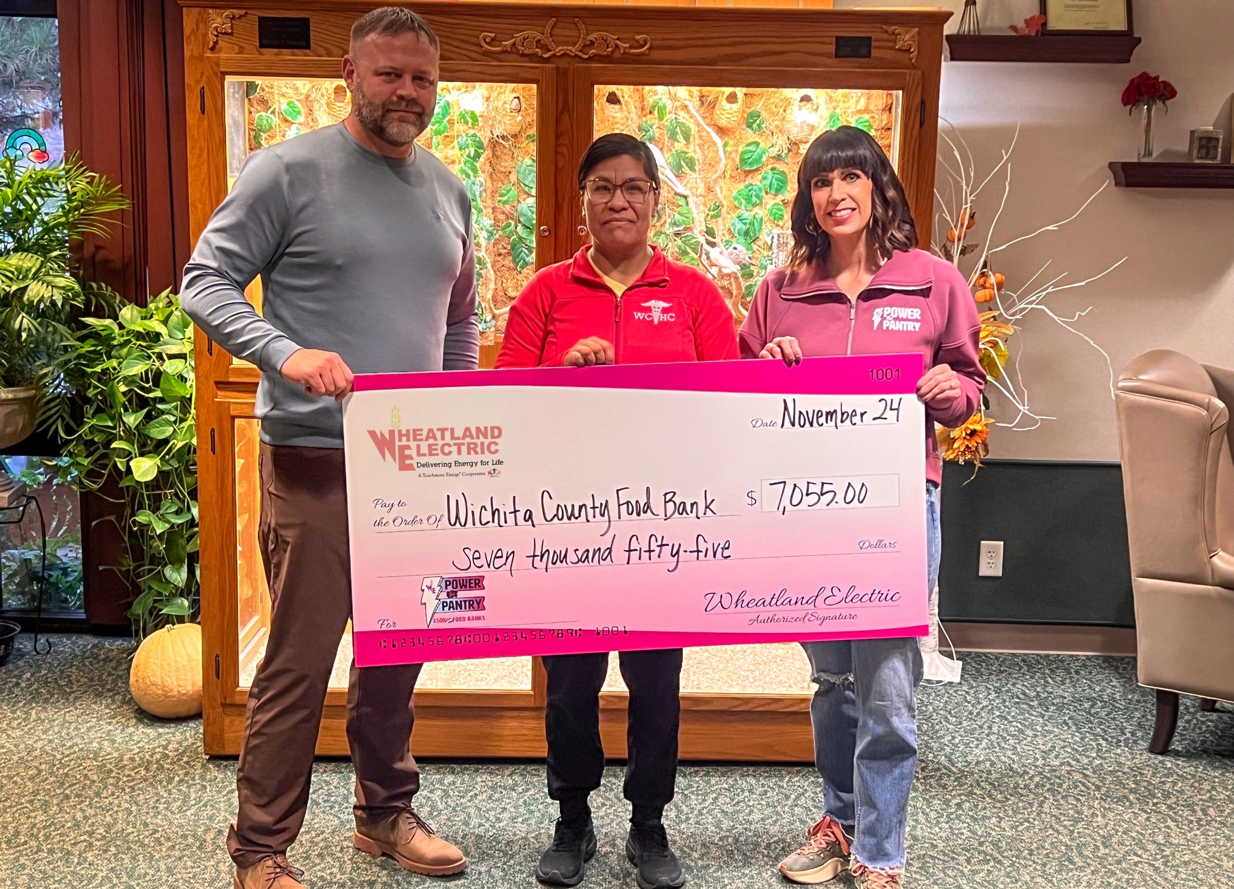 Alli Conine (right), director of member services and corporate communications at Wheatland Electric, and Josh Young, trustee (left), present a check for $7,055 to Mirna Jimenez (center) of the Wichita County Food Bank. 