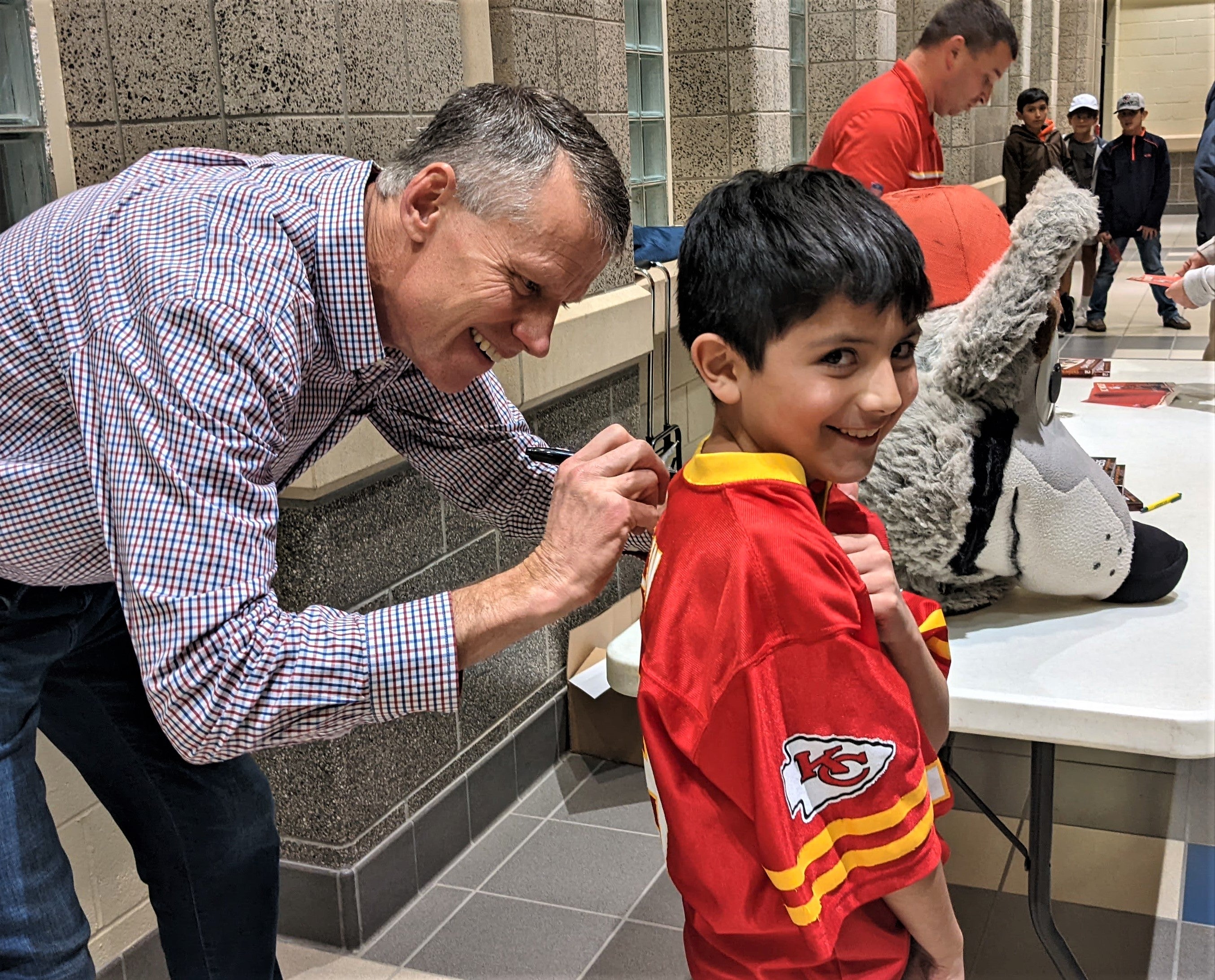 KC Wolf autographs the back of a kid's jersey